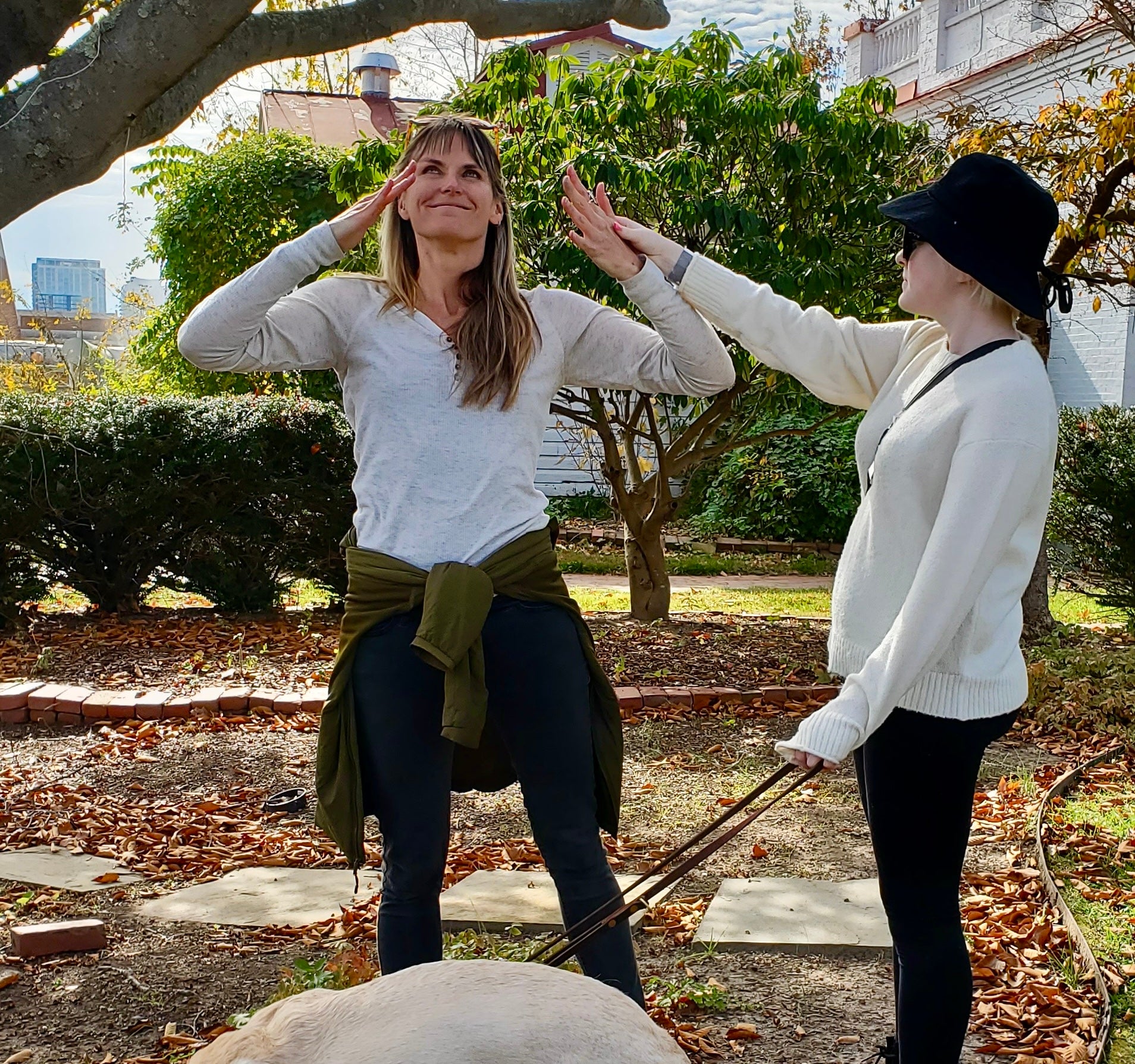 A student and her guide dog engage with the presenter's performance in a garden on a sunny fall day.